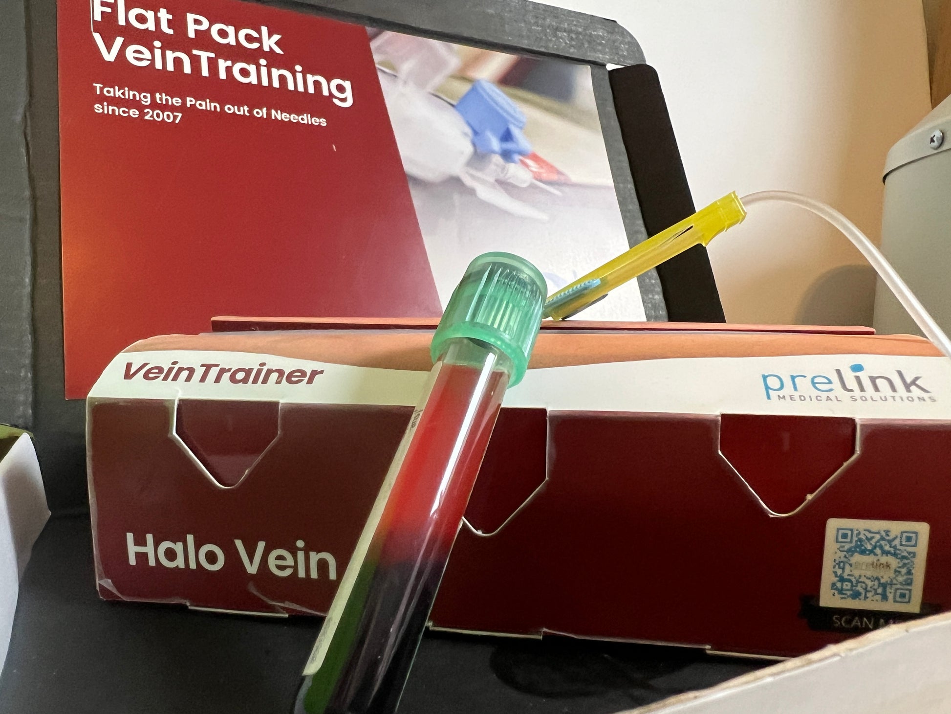 Halo Vein vein training device with a box labeled 'VeinTrainer' and 'prelink'.  VeinTrain flat-pack vein simulator for phlebotomy and cannulation training
