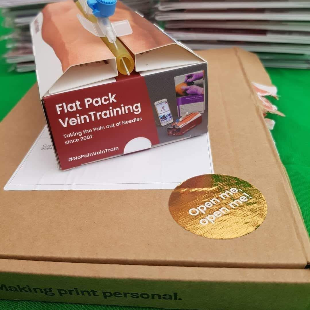 Box with 'Flat Pack Vein Training' packaging on a green surface.VeinTrain flat-pack vein simulator for phlebotomy and cannulation training
