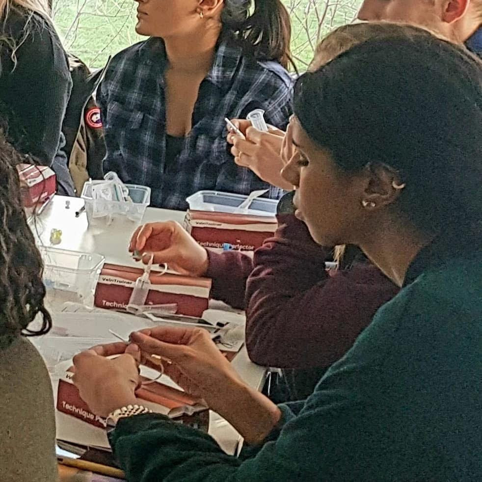 Group of people at a table using VeinTrain flat-pack vein simulator for phlebotomy and cannulation training
